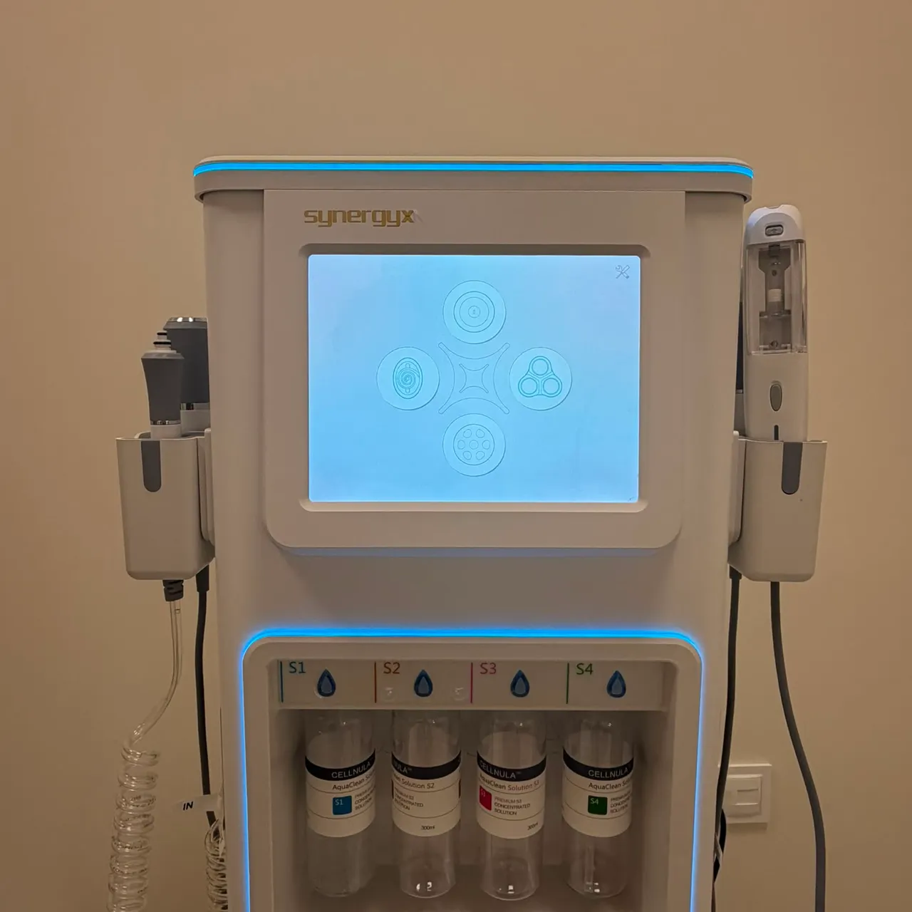 Wielofunkcyjne urządzenie do pielęgnacji i oczyszczania twarzy Synergy X z pojemnikami na preparaty i ekranem dotykowym.